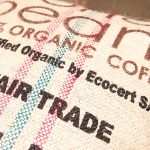 Photo of burlap bag of Coffee beans. Text on the bag says, 100% Organic Coffee. Certified Organic by Ecocert SA. Fair Trade.
